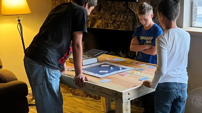 3 young boys playing monopoly on their new pine puzzle/games table